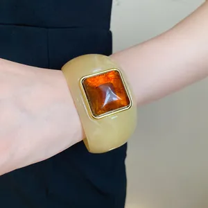 Detailed macro view of a chunky cream acrylic bangle with large square amber resin inlay