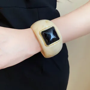 Detailed close-up of a marbled cream acrylic cuff bracelet with a square black glossy inset