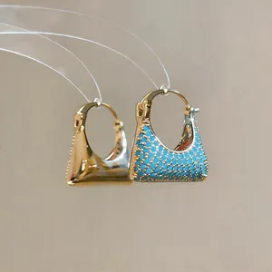 Nahaufnahme von handtaschenförmigen Ohrringen mit 18k Goldbeschichtung und blauen Zirkonia.