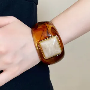 Close-up of vintage amber acrylic bangle featuring a unique marble square inset and gold trim