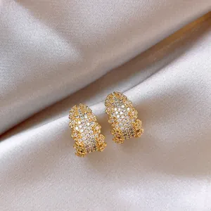 Dettaglio di eleganti orecchini a lobo a forma di C in oro con pavé di zirconi cubici