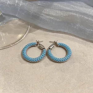 Elegante silberne Creolen mit leuchtenden türkisfarbenen Perlen in modernem Stil.