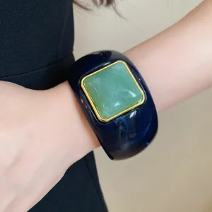 Close-up of a wide navy blue acrylic cuff bracelet with a green square resin inlay