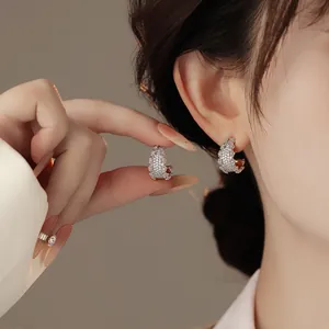 Dettaglio degli orecchini a C in argento con pavé di diamanti indossati sull'orecchio