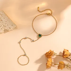 Vue détaillée d'un élégant bracelet de doigt en or avec un cristal vert en forme de cœur