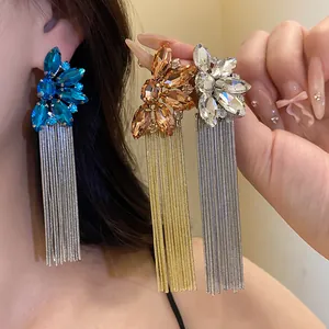 Close-up of sparkling crystal flower tassel earrings in blue, gold, and silver colors.