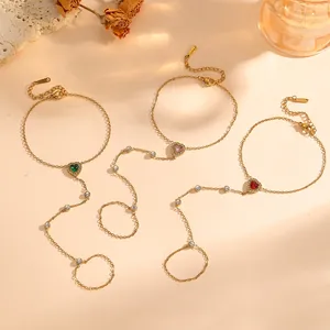Détail de la gourmette de main en acier doré avec gemmes colorées en forme de cœur.