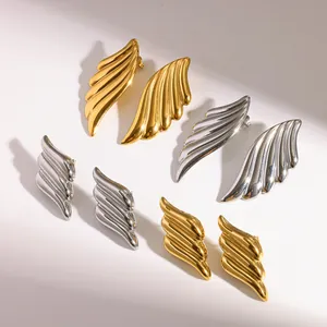 Close-up of stylish angel wing stud earrings in gold and silver plated finish.