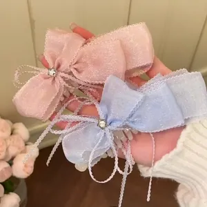 Paire de pinces à cheveux avec nœud en dentelle, tissu pailleté et strass pour femme.