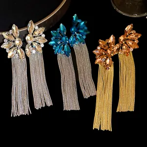 Close-up of crystal flower tassel earrings in silver, blue, and gold colors.