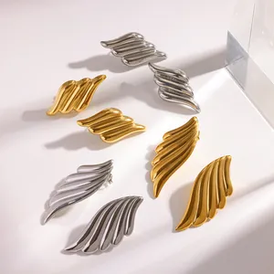 Detailed view of gold and silver angel wing stud earrings on a minimalist white background