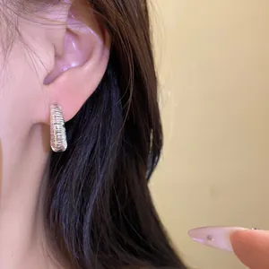 Dettaglio di orecchini a cerchio in argento con texture vintage indossati sull'orecchio