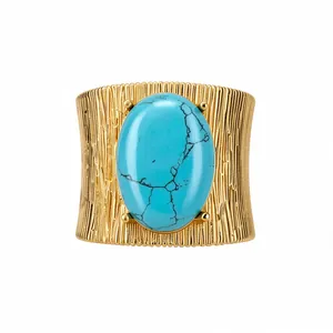 Bracciale rigido vintage in metallo dorato con grande pietra turchese ovale blu.