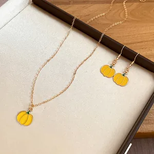 Close-up of yellow enamel pumpkin pendant necklace and earrings set in a jewelry gift box