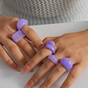 Close-up view of five lavender marbled resin rings worn on the hands of a model.