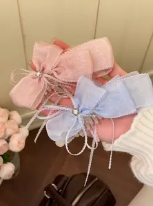 Vue détaillée de pinces à cheveux à nœud en dentelle douce avec strass en rose et bleu