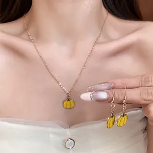 Detail view of sweet enamel pumpkin pendant necklace and matching earrings set