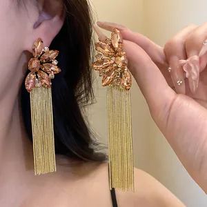 Detail of champagne crystal flower earrings featuring elegant long gold chain tassels