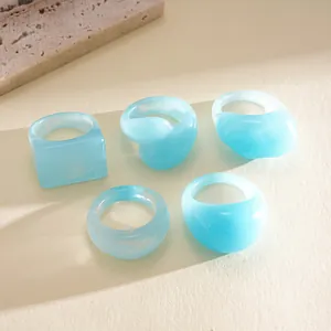 Detailed macro view of 5-piece light blue dyed resin rings with various geometric shapes