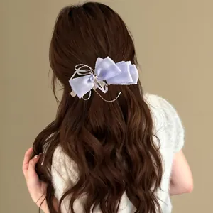 Élégante pince à cheveux nœud en dentelle lilas clair sur cheveux longs et bouclés bruns