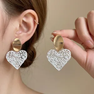 Elegant hollow heart-shaped earrings with gold accents for a luxury summer fashion look.