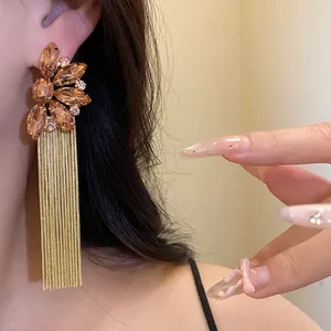 Detailed view of champagne crystal flower earrings with elegant long gold fringe tassels
