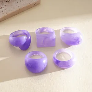 Macro detail shot of a five-piece purple marbled resin ring set in various geometric shapes.
