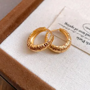 Vista macro di orecchini a cerchio in oro vintage con eleganti trame a coste
