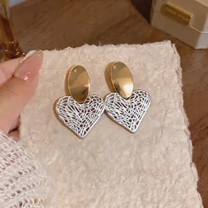 Elegant gold and white hollow heart-shaped stud earrings for chic summer resort style.