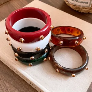 Vintage Harzarmbänder mit Goldnieten und Tigerauge-Steinen in verschiedenen Farben.
