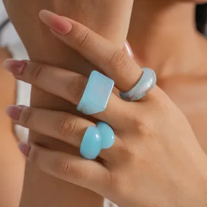 Close-up of blue marbled resin rings in geometric shapes on a model's hand