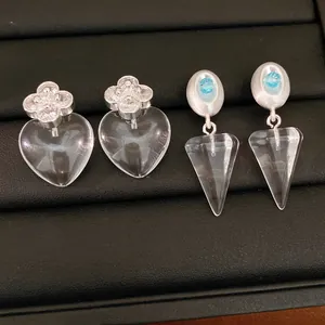 Detailed view of silver heart and cone earrings with blue accents on a black jewelry tray