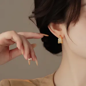 Dettaglio di eleganti orecchini a forma di C dorati con strass indossati da una modella asiatica
