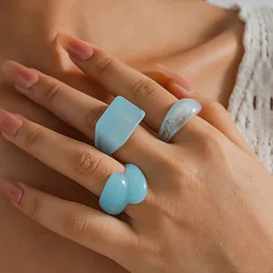 Close-up view of a set of light blue resin marble rings featuring geometric shapes
