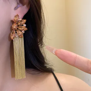 Close-up of champagne crystal flower tassel earrings with gold chain fringe worn on ear