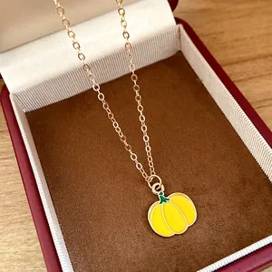 Detailed macro view of a sweet yellow enamel pumpkin pendant on a delicate gold chain necklace