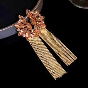 Close-up of elegant champagne crystal flower earrings featuring long gold chain tassels
