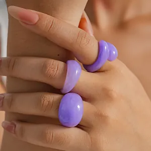 Purple marbled resin rings worn on fingers in a close-up detail shot.