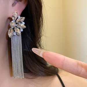 Macro view of elegant silver needle floral crystal tassel earrings worn on a model's ear