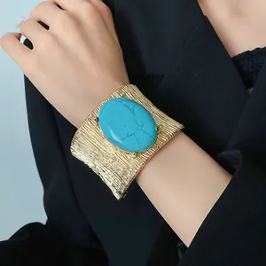 Dettaglio di un bracciale a polsino dorato vintage con una grande pietra turchese