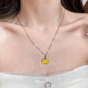 Close-up of a sweet enamel pumpkin pendant necklace on a gold-tone chain