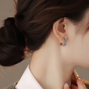 Primo piano di eleganti orecchini a lobo a forma di C in argento con diamanti pavé