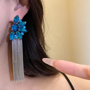 Close-up of blue gemstone flower earrings with long silver tassel chains