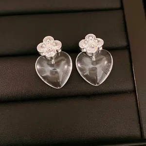 Close-up detail of silver needle earrings with zircon flower and clear resin hearts