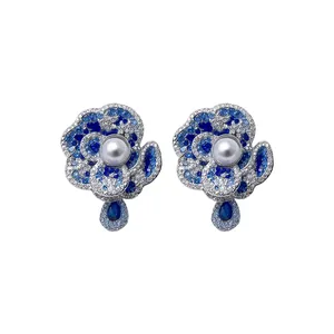 Elegant floral stud earrings featuring blue crystals and a radiant central white pearl