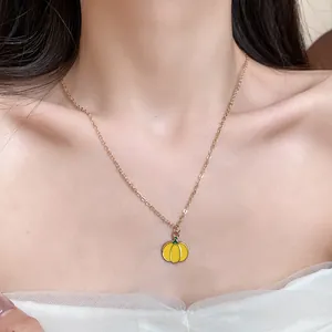 Detail shot of a sweet yellow enamel pumpkin pendant necklace on a model's neck