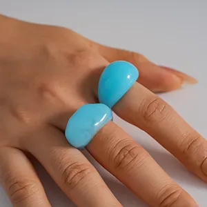 Close-up detail of stylish light blue chunky resin geometric rings worn on a hand
