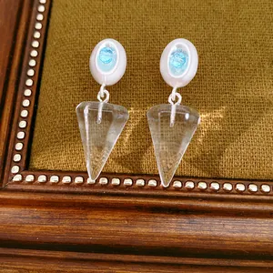 Detailed view of ice blue dangle earrings with cone-shaped resin pendants and silver finish