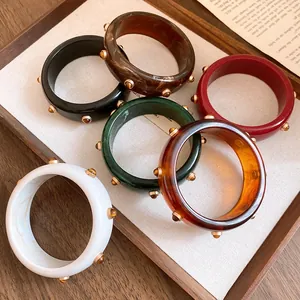 Detailansicht einer Kollektion von Vintage-Resin-Armreifen mit goldfarbenen Nieten