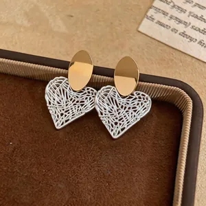 Close-up of elegant hollow wireframe heart earrings with gold-tone oval stud tops